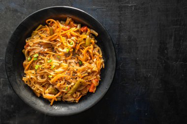 Kızarmış erişteyi sebze ve baharatla karıştır, yakından bak.