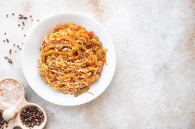 Kızarmış erişteyi sebze ve baharatla karıştır, yakından bak.