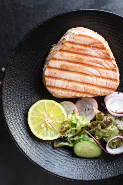 Izgara somon bifteği, sebze salatası tabakta, yakın çekim manzaralı.