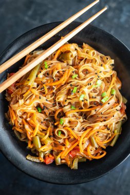 Kızarmış erişteyi sebze ve baharatla karıştır, yakından bak.