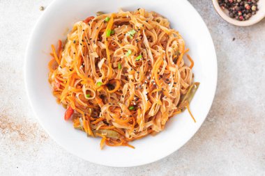 Kızarmış erişteyi sebze ve baharatla karıştır, yakından bak.