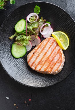 Izgara somon bifteği, sebze salatası tabakta, yakın çekim manzaralı.