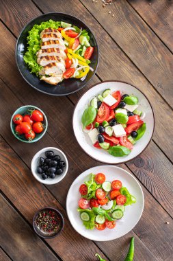 farklı salatalar sebzeler, ızgara tavuk göğsü, zeytin, feta, domates, soğan, salatalık masada diğer sağlıklı yiyecekler.