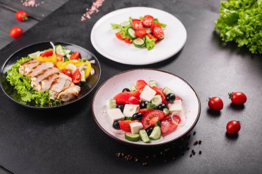 farklı salatalar sebzeler, ızgara tavuk göğsü, zeytin, feta, domates, soğan, salatalık masada diğer sağlıklı yiyecekler.