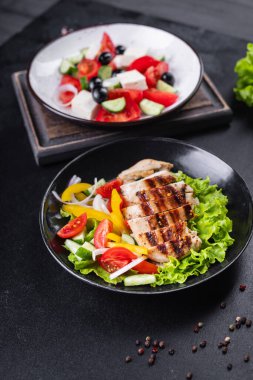 farklı salatalar sebzeler, ızgara tavuk göğsü, zeytin, feta, domates, soğan, salatalık masada diğer sağlıklı yiyecekler.