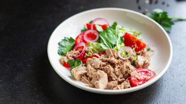 Ton balıklı salata sebzeli domates, soğan, otlar, zeytinli konserve ton balığı tabağı masada sağlıklı yemek fotokopisi, arka plan manzarası.  