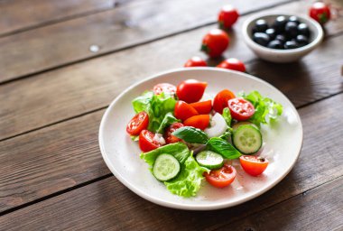 Salata sebzesi, salatalık, domates, soğan, marul yemeği organik ürünler, atıştırmalık uzay yiyecek arka planının kırsal kopyası. Top view keto ya da paleo diyet vejetaryen ya da vejetaryen yemekleri 