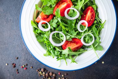 Arugula ve domates salatası taze bir porsiyonda hazır yemek atıştırmalığı için fotokopi uzayı arka plan kırsalında. Top view keto ya da paleo diyet vejetaryen ya da vejetaryen yemekleri