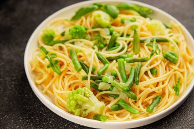 Spagetti sebzesi, bezelye, brokoli, çalı fasulyesi, kohlrabi vejetaryen makarna lezzetli makarna masanın üzerinde taze lezzetli gurme yemek.