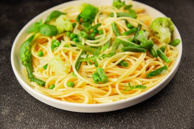 Spagetti sebzesi, bezelye, brokoli, çalı fasulyesi, kohlrabi vejetaryen makarna lezzetli makarna masanın üzerinde taze lezzetli gurme yemek.
