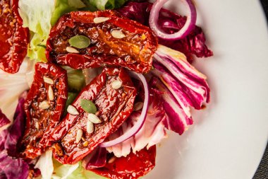 Salata, kurutulmuş domates, yeşil yaprak, soğan, doğal ürün, lezzetli aperatif. Lezzetli gurme yemek arkaplanı, masa, rustik üst manzara, fotokopi alanı, vejetaryen diyeti ve vejetaryen yemeği.