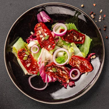 Salata, kurutulmuş domates, yeşil yaprak, soğan, doğal ürün, lezzetli aperatif. Lezzetli gurme yemek arkaplanı, masa, rustik üst manzara, fotokopi alanı, vejetaryen diyeti ve vejetaryen yemeği.