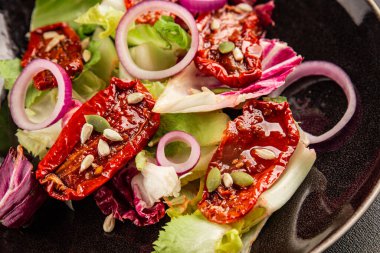 Salata, kurutulmuş domates, yeşil yaprak, soğan, doğal ürün, lezzetli aperatif. Lezzetli gurme yemek arkaplanı, masa, rustik üst manzara, fotokopi alanı, vejetaryen diyeti ve vejetaryen yemeği.