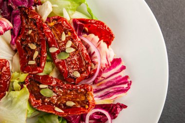 Salata, kurutulmuş domates, yeşil yaprak, soğan, doğal ürün, lezzetli aperatif. Lezzetli gurme yemek arkaplanı, masa, rustik üst manzara, fotokopi alanı, vejetaryen diyeti ve vejetaryen yemeği.