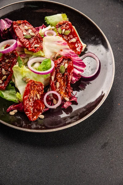 Salata, kurutulmuş domates, yeşil yaprak, soğan, doğal ürün, lezzetli aperatif. Lezzetli gurme yemek arkaplanı, masa, rustik üst manzara, fotokopi alanı, vejetaryen diyeti ve vejetaryen yemeği.
