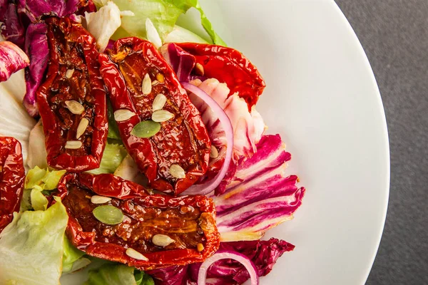 Salata, kurutulmuş domates, yeşil yaprak, soğan, doğal ürün, lezzetli aperatif. Lezzetli gurme yemek arkaplanı, masa, rustik üst manzara, fotokopi alanı, vejetaryen diyeti ve vejetaryen yemeği.