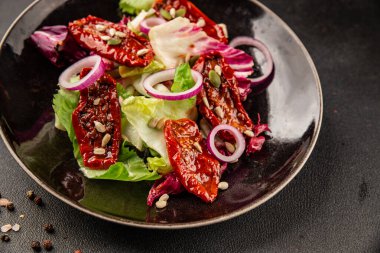 Salata, kurutulmuş domates, yeşil yaprak, soğan, doğal ürün, lezzetli aperatif. Lezzetli gurme yemek arkaplanı, masa, rustik üst manzara, fotokopi alanı, vejetaryen diyeti ve vejetaryen yemeği.