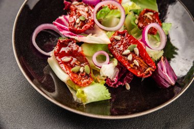 Salata, kurutulmuş domates, yeşil yaprak, soğan, doğal ürün, lezzetli aperatif. Lezzetli gurme yemek arkaplanı, masa, rustik üst manzara, fotokopi alanı, vejetaryen diyeti ve vejetaryen yemeği.
