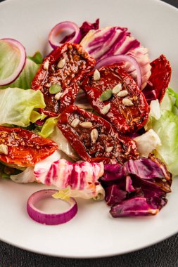 Salata, kurutulmuş domates, yeşil yaprak, soğan, doğal ürün, lezzetli aperatif. Lezzetli gurme yemek arkaplanı, masa, rustik üst manzara, fotokopi alanı, vejetaryen diyeti ve vejetaryen yemeği.