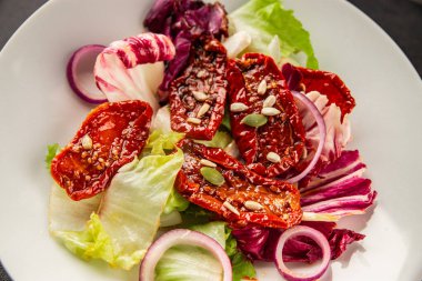 Salata, kurutulmuş domates, yeşil yaprak, soğan, doğal ürün, lezzetli aperatif. Lezzetli gurme yemek arkaplanı, masa, rustik üst manzara, fotokopi alanı, vejetaryen diyeti ve vejetaryen yemeği.