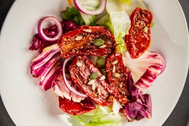 Salata, kurutulmuş domates, yeşil yaprak, soğan, doğal ürün, lezzetli aperatif. Lezzetli gurme yemek arkaplanı, masa, rustik üst manzara, fotokopi alanı, vejetaryen diyeti ve vejetaryen yemeği.