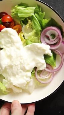 Burrata peyniri domates, mor soğan, yeşil yaprak marul lezzetli aperatif taze gurme yemek masası kırsal yiyeceklerin üst görünümü fotokopi alanı keto ve paleo diyet vejetaryen yemeği.