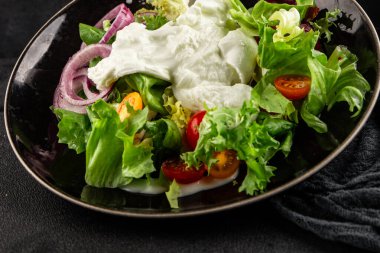 Burrata salatası domates, mor soğan, yeşil yaprak marul lezzetli aperatif taze gurme yemek masası kırsal yemek üst görünüm fotokopi alanı keto ve paleo diyet vejetaryen yemeği.