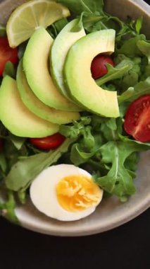 Avokado salatası roka, yumurta, domates, karışık yeşillikler, sebzeler taze yemek arka plan gurmesi masa üstü kırsal yemek fotokopi alanı keto ve paleo diyet vejetaryen yemeği.