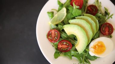 Avokado salatası roka, yumurta, domates, karışık yeşillikler, sebzeler taze yemek arka plan gurmesi masa üstü kırsal yemek fotokopi alanı keto ve paleo diyet vejetaryen yemeği.