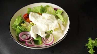 Burrata salatası domates, mor soğan, yeşil yaprak marul lezzetli aperatif taze gurme yemek masası kırsal yemek üst görünüm fotokopi alanı keto ve paleo diyet vejetaryen yemeği.
