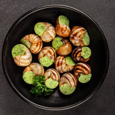 Salyangoz yemeği, yeşil tereyağı, Fransız mutfağı, yemek, lezzetli aperatif, lezzetli gurme yemek arka planı, masa kırsal yiyeceklerin üst görünümü, fotokopi alanı.