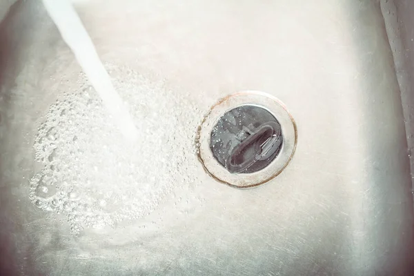 Wasserstrahl strömt in einer Spüle mit Set-Ablassstopfen — Stockfoto