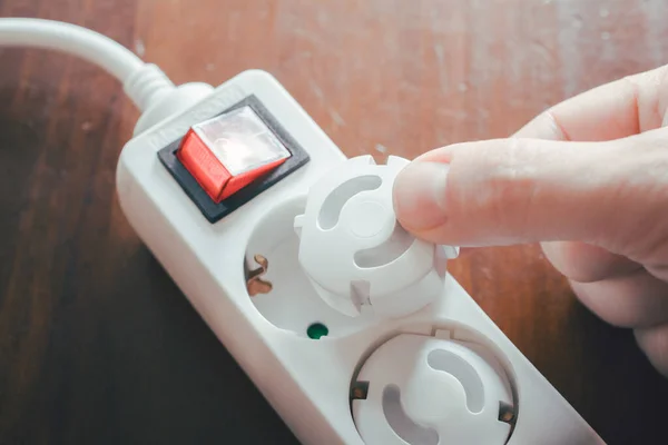 Hand Inserting Baby Safety Plugs Into Power Strip - Child Safety Concept