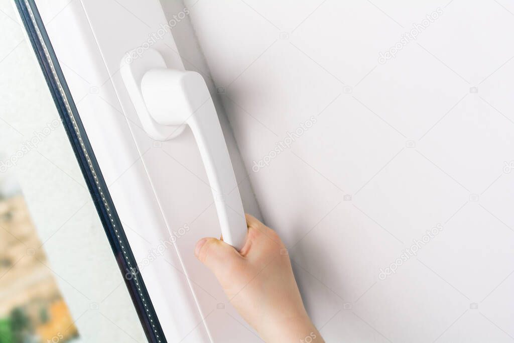 Child Hand Trying To Open A Window Handle Of A Closed White Window - Prevent Child Hazard Concept