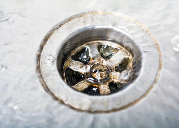 Etwas Wasser gießt einen schmutzigen Abfluss in einer Küchenspüle herunter — Stockfoto