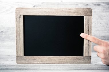 Bir arkaplanın önündeki boşluğu kopyalayan boş bir karatahtaya işaret eden parmak