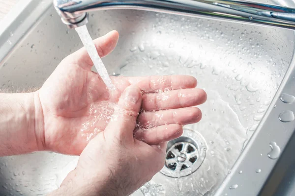 Männchen wäscht sich die Hände im Wasserstrom an einer Küchenspüle — Stockfoto