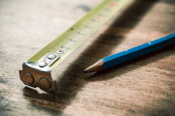 Ołówek i taśma pomiarowa na zabytkowym drewnianym stole — Zdjęcie stockowe
