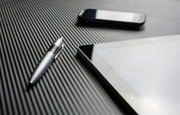 Blank Smartphone With Reflection And A Pen Lying Next To A Business Tablet On A Carbon Layer — Zdjęcie stockowe