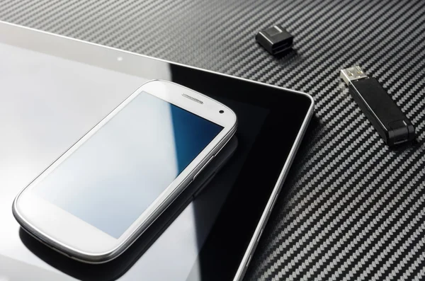 Blank Smartphone With Blue Reflection Lying On Business Tablet Next To An Open USB Storage Flash Drive Above A Carbon Background — Stockfoto