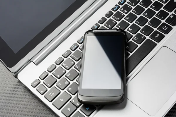 Smartphone business nero vuoto con riflesso sdraiato su una tastiera del taccuino, tutto sopra uno strato di carbonio — Foto Stock