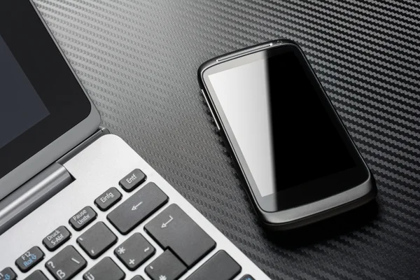 Business Work With Black Smartphone With Reflection Lying Right To A Notebook Keyboard, All Above A Carbon Layer — 스톡 사진