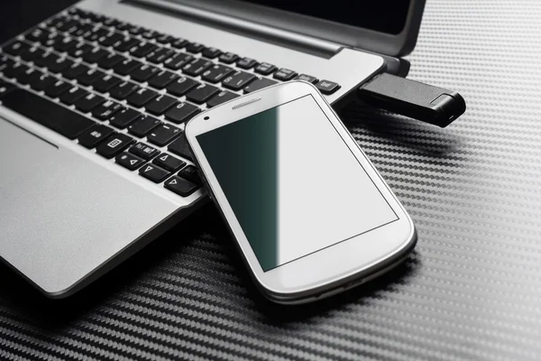 Boş beyaz telefon ile A Usb depolama birden parlamak götürmek, tüm karbon tabaka üzerinde takılı yanında iş dizüstü bilgisayar klavyesindeki eğilerek yeşil yansıma