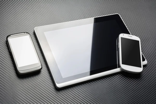 Blank svart mobil ligga bredvid en Business Tablet med reflektion och en vit Smartphone på det är hörn, alla över ett kol lager — Stockfoto
