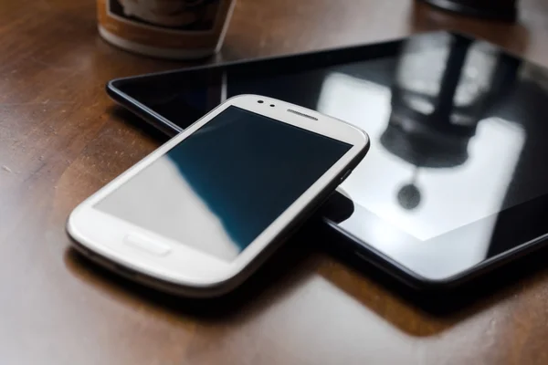 Smartphone angelehnt an Tablet mit Kaffee & Kaffeemaschine im Hintergrund — Stockfoto