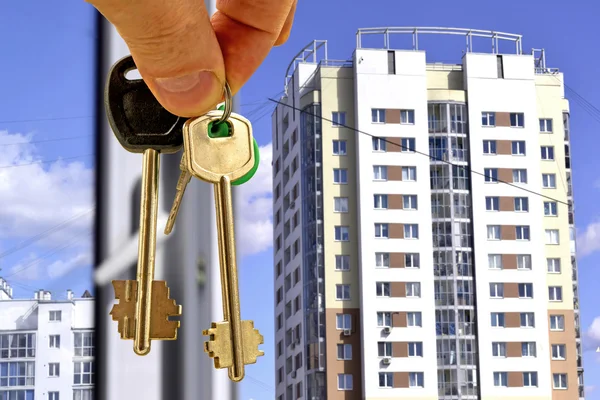 The keys to the apartment in hand on the background of new homes Stock Picture