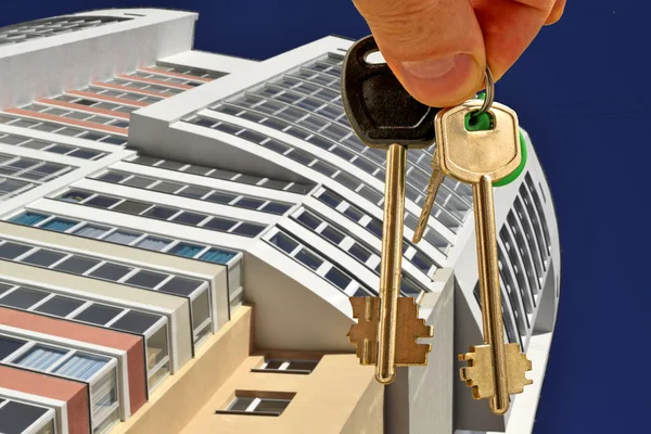 The keys to the apartment in hand on the background of new homes Stock Image