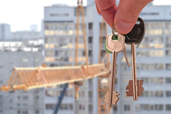 A kulcsokat a lakás a kezében a háttérben a házak — Stock Fotó