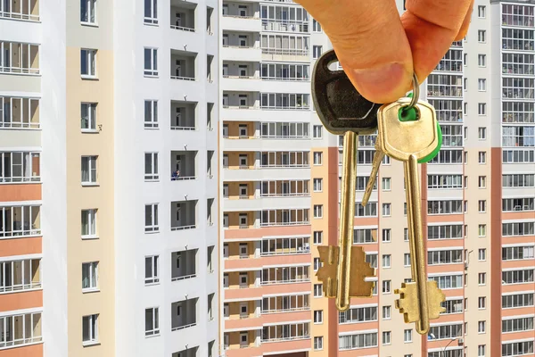 Die Schlüssel zur Wohnung in der Hand auf dem Hintergrund von Häusern — Stockfoto