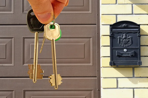 De sleutels van het appartement in hand op de achtergrond van huizen — Stockfoto